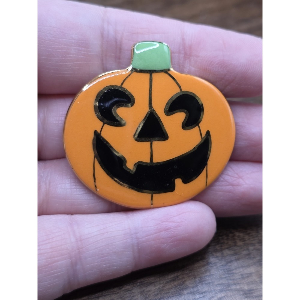 enamel pumpkin Pin features a vibrant orange jack-o'-lantern design